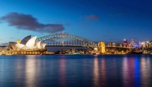 Photograph capturing the iconic view of Australia's Sydney Opera House with the Sydney Harbour Bridge by its side, showcasing a landmark-filled cityscape.