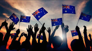 Photograph displaying the shadow of numerous hands holding the Australian flag, creating a patriotic and united visual.
